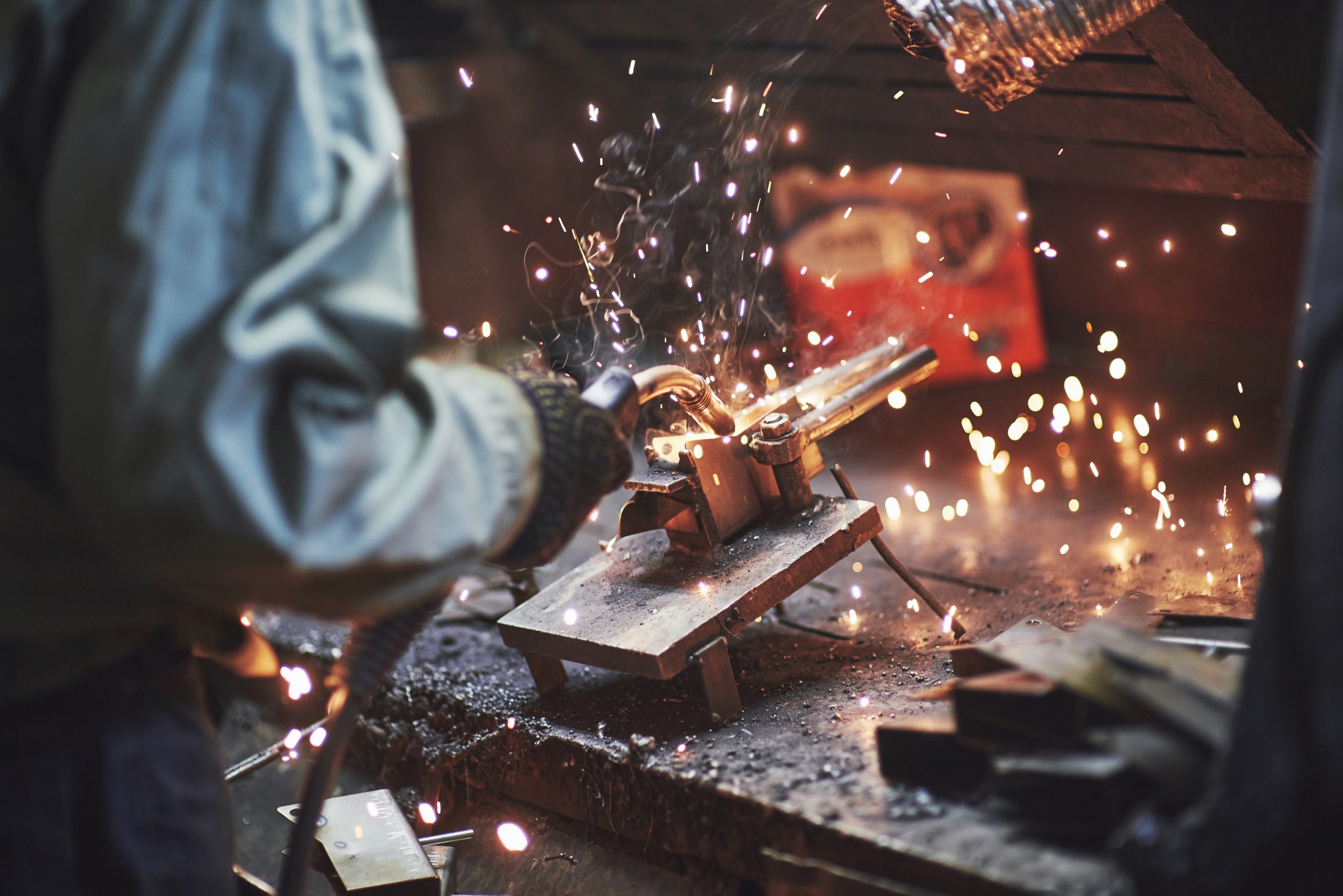 Close-up of a welder's torch throwing sparks across a steel workpiece